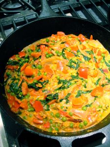 Tomato Coconut Curry finished with coconut cream and fresh spinach leaves.