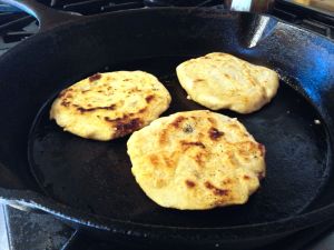 Cooking pupusas in an oiled pan.
